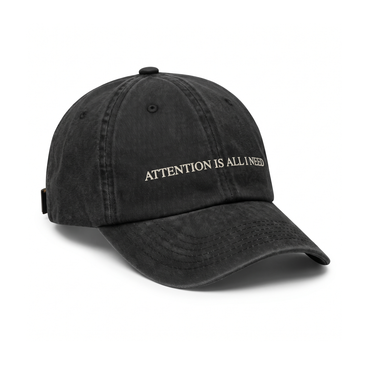 Washed black six-panel cap with ATTENTION IS ALL I NEED embroidered in small ivory serif capitals